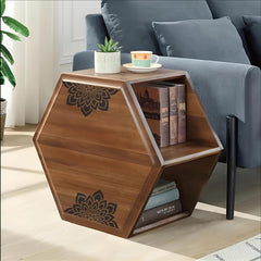 Hexagonal wooden side table with decorative patterns, books, and a cup on a sofa in a living room.
