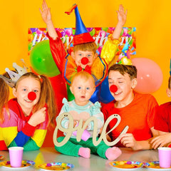 Children at a birthday party with colorful decorations and clown noses.