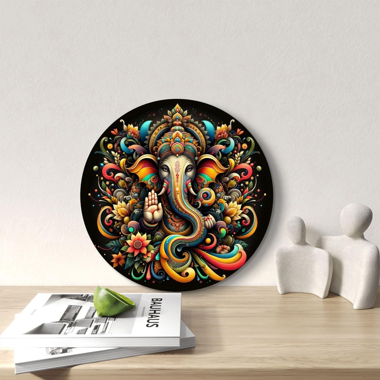 Decorative circular piece with colorful Ganesha design on a table with a magazine and lime.