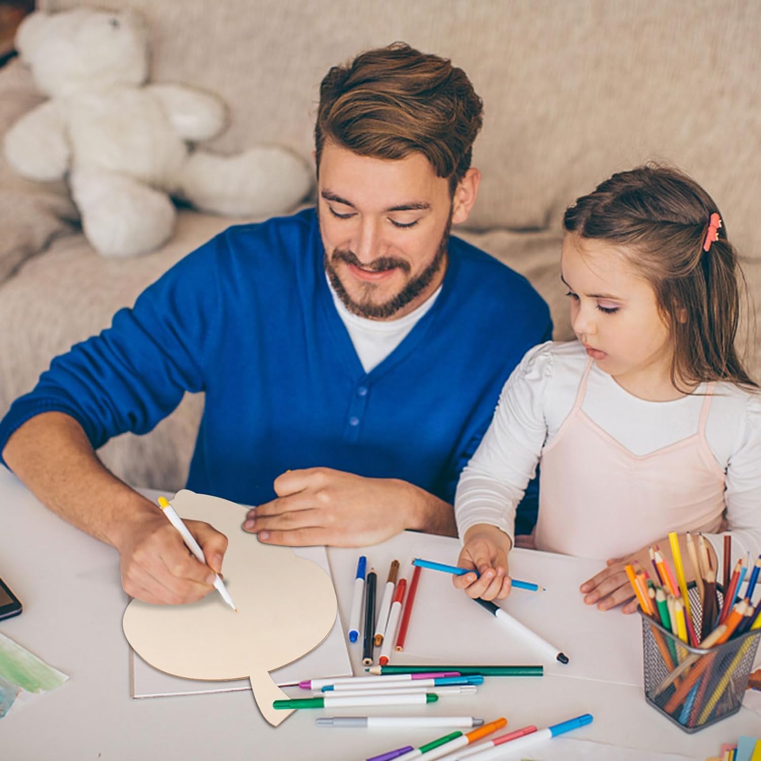 Man and young girl coloring together at a table with markers and paper.