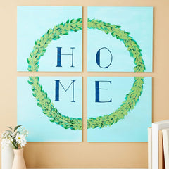 Four square wall art pieces with green leafy wreaths and blue letters spelling 'HOME' on a beige wall.