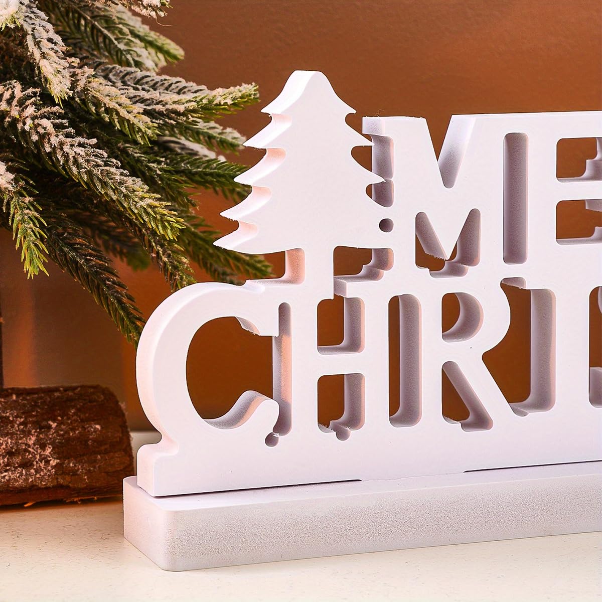 Decorative Christmas sign with cut-out letters in front of a Christmas tree.