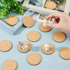 Wooden coasters with small animal figurines on a light blue surface, hand placing another figurine.