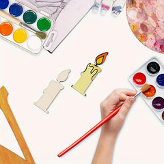 Artistic activity with watercolor paints, brushes, and candle-shaped objects on a white surface.