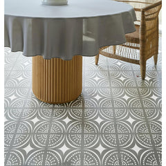 Round table with a gray tablecloth on a patterned floor