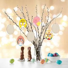 Decorative Easter setup with branches, eggs, and small signs on a blurred light background