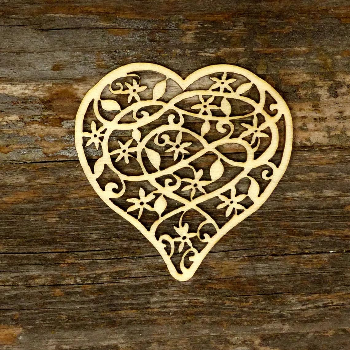 Decorative heart-shaped cutout with intricate patterns on a wooden surface