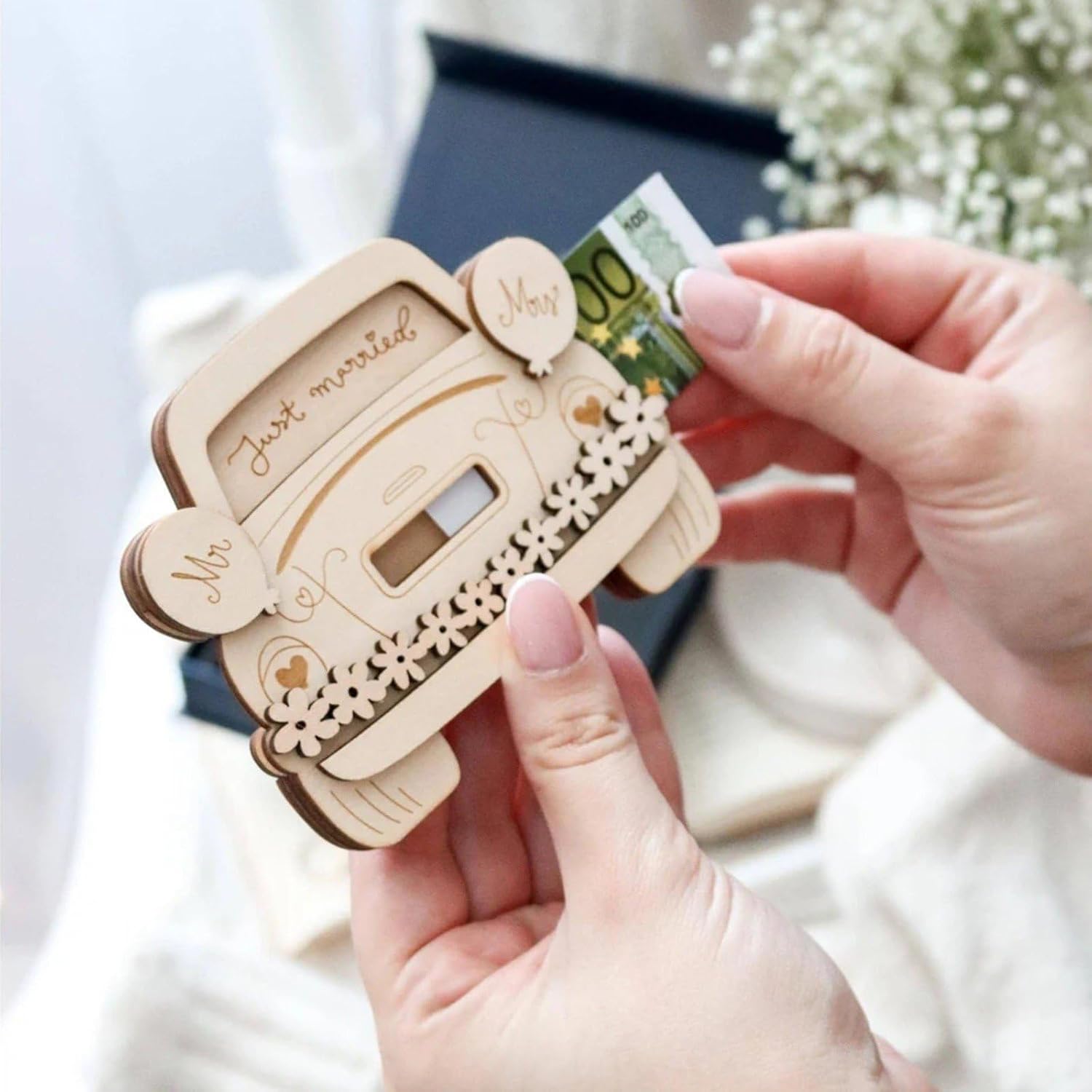 Wooden card with 'Just married' text and a money holder, held by hands.