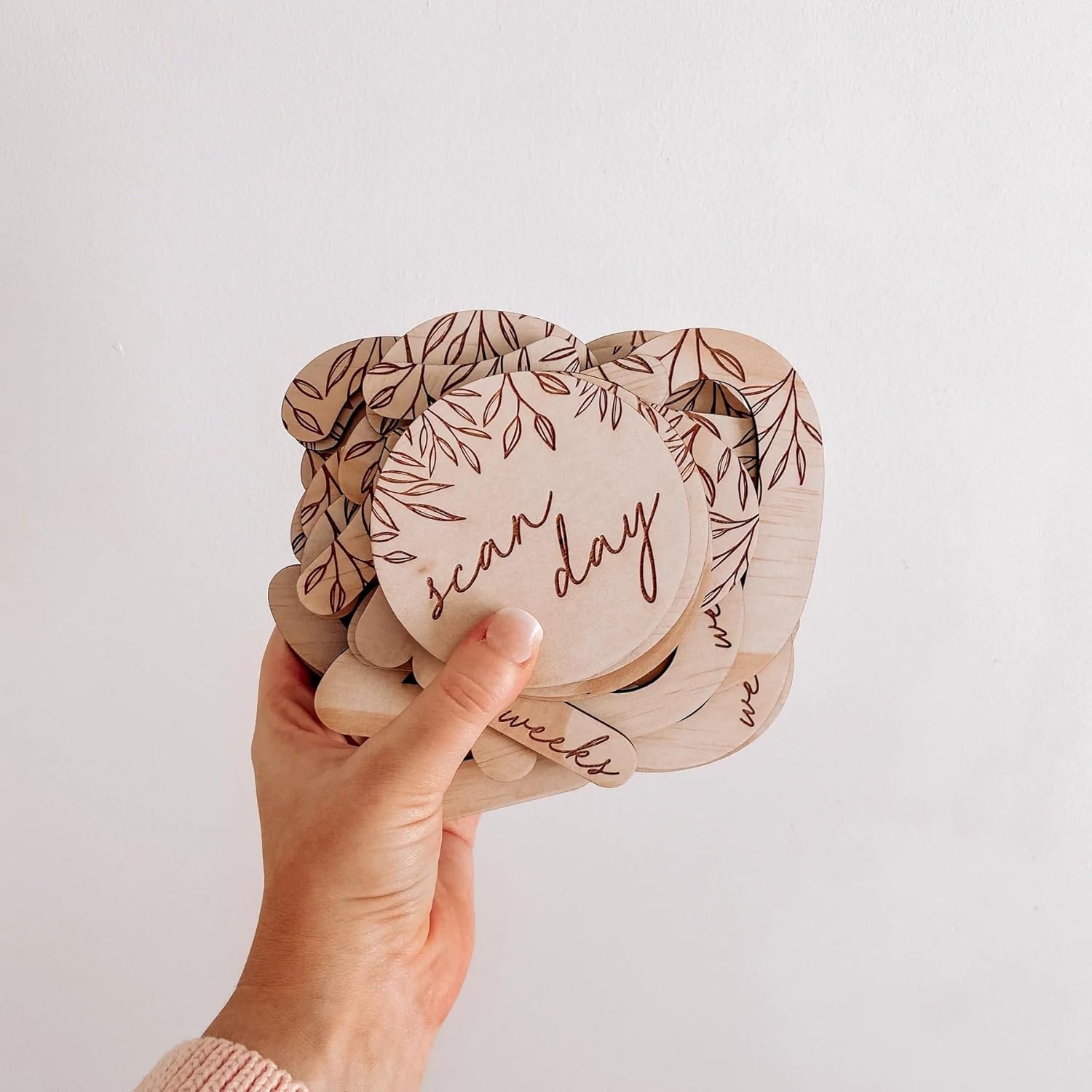 Hand holding a wooden product with 'scar day' and 'wax week' text on a plain background