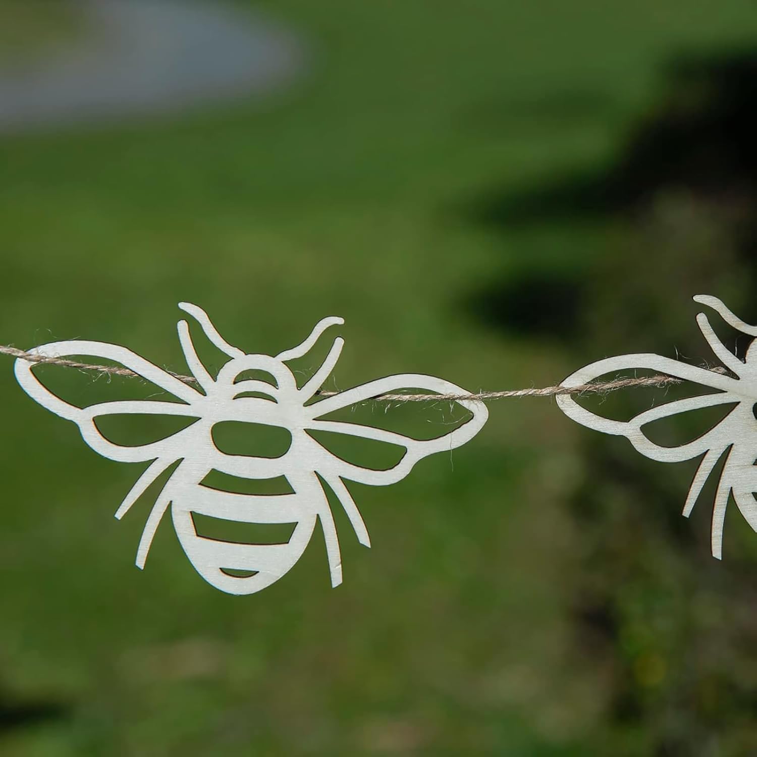 Decorative string with white bee cutouts against a blurred green background