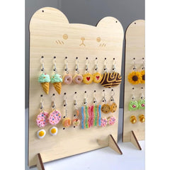 Wooden earring display with various colorful earrings on a white background
