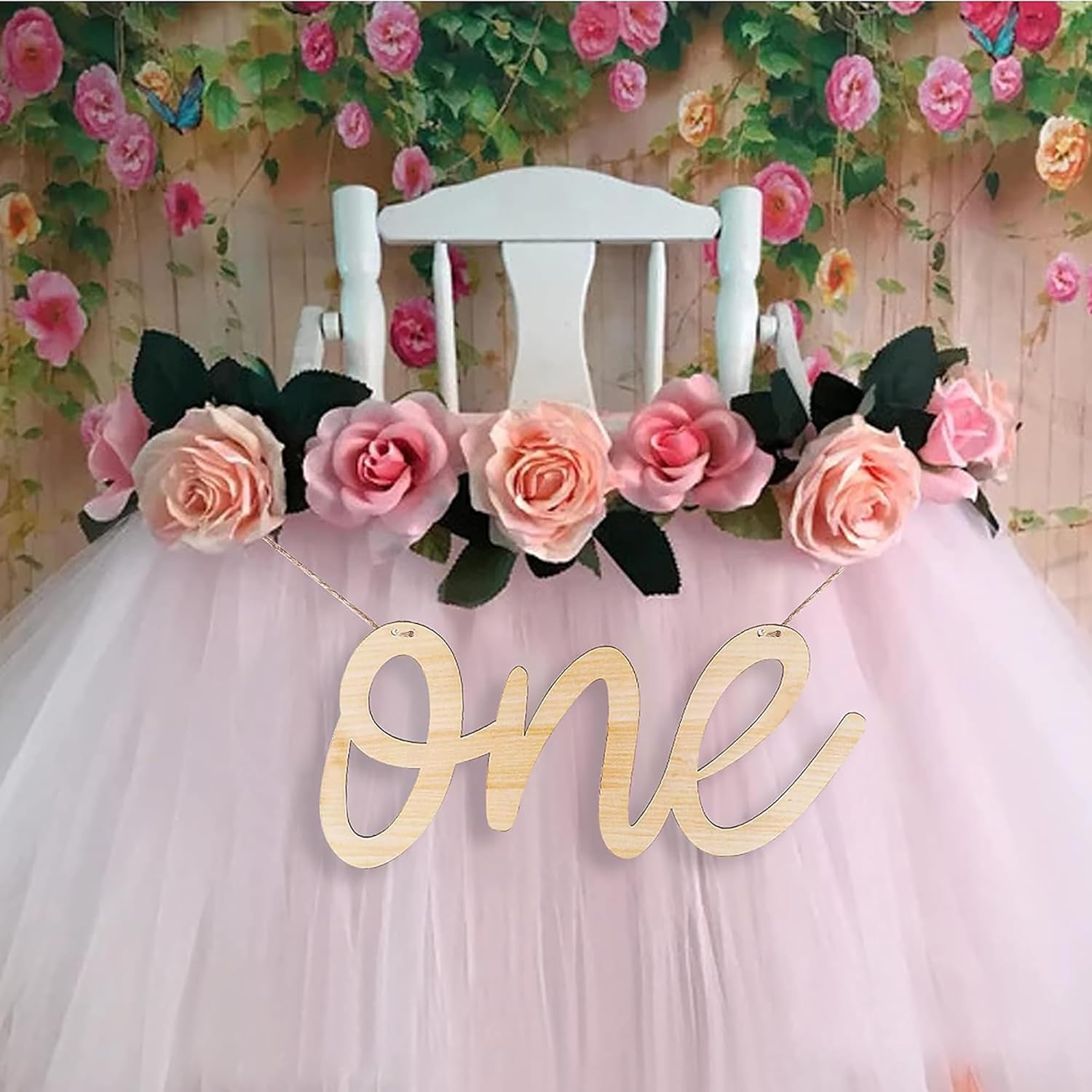 Chair with floral decorations and a 'one' sign against a floral backdrop