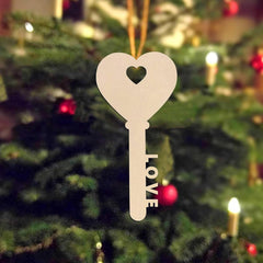 Decorative key-shaped ornament with a heart cutout and 'LOVE' text, hanging on a Christmas tree.