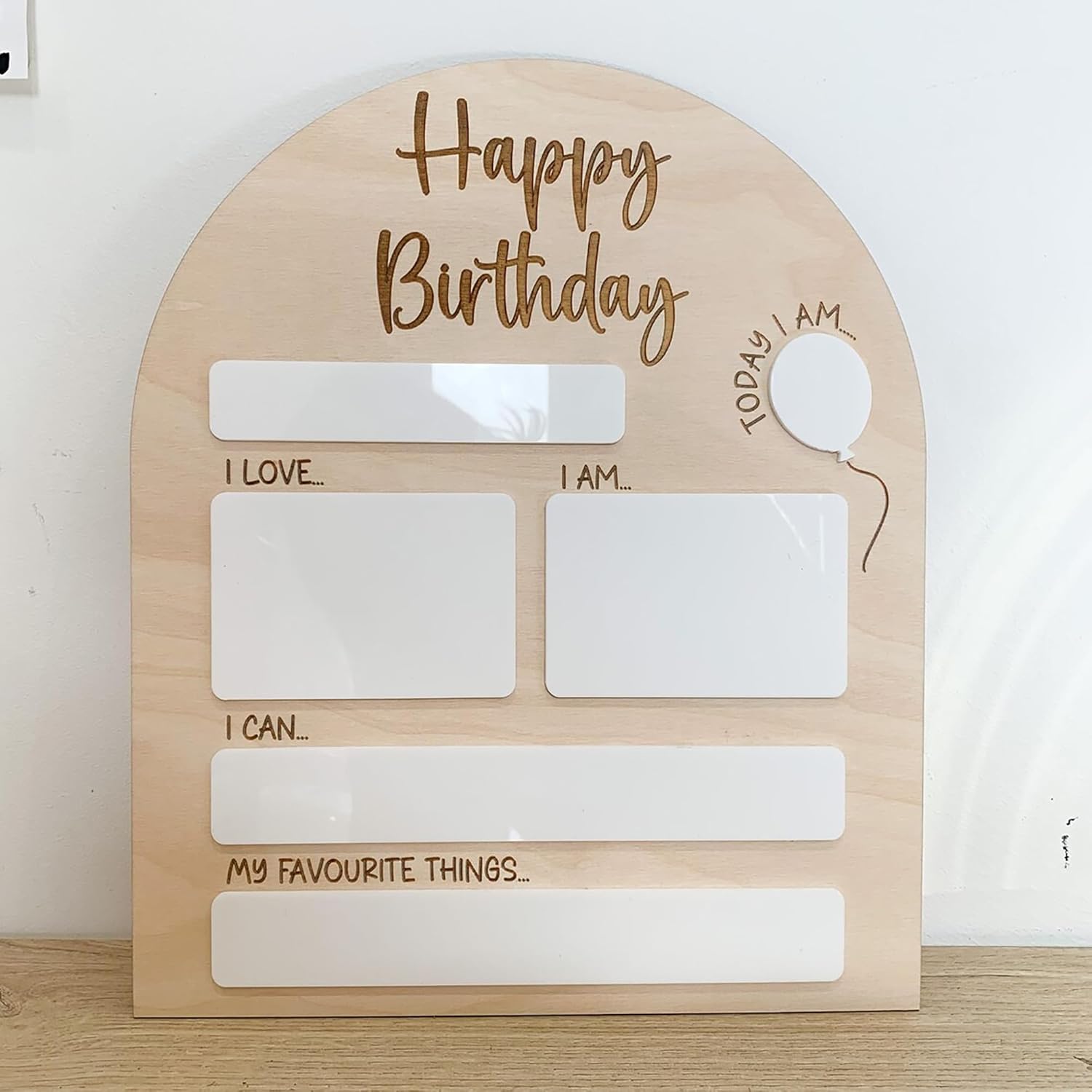 Wooden board with 'Happy Birthday' text and blank sections for writing on a white background