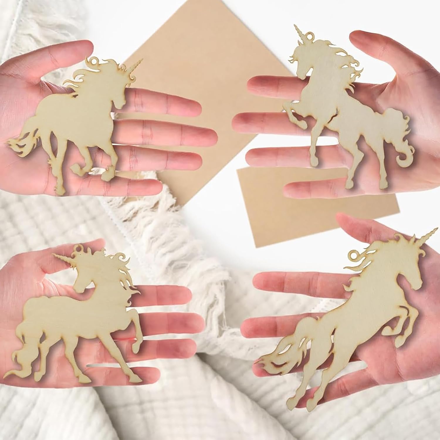 Unicorn-shaped wooden cutouts held in hands against a white background