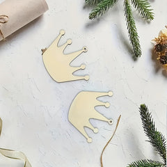 Gold crown-shaped decorations on a textured white surface with greenery.