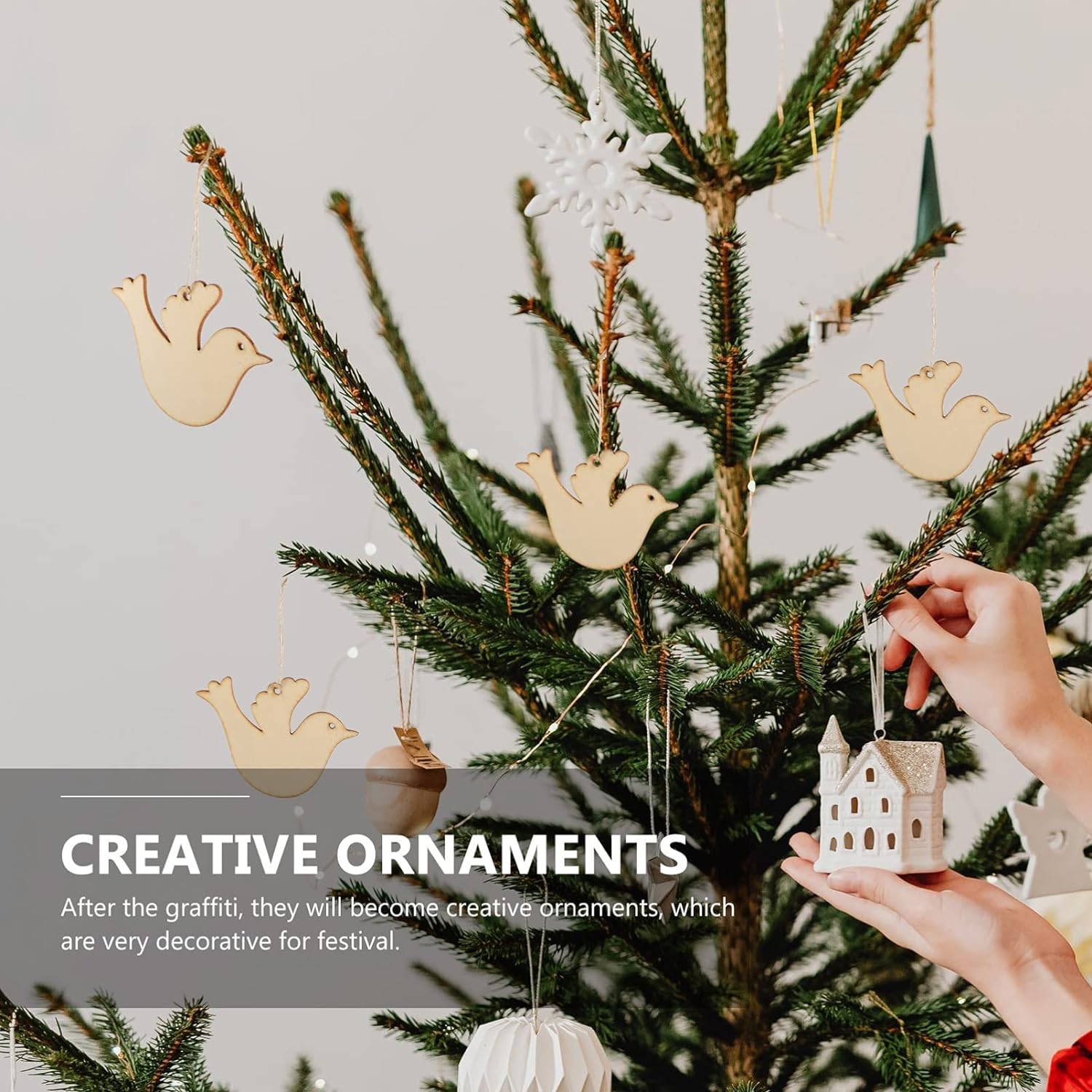 Decorative Christmas tree with creative ornaments including birds and a house, against a neutral background.