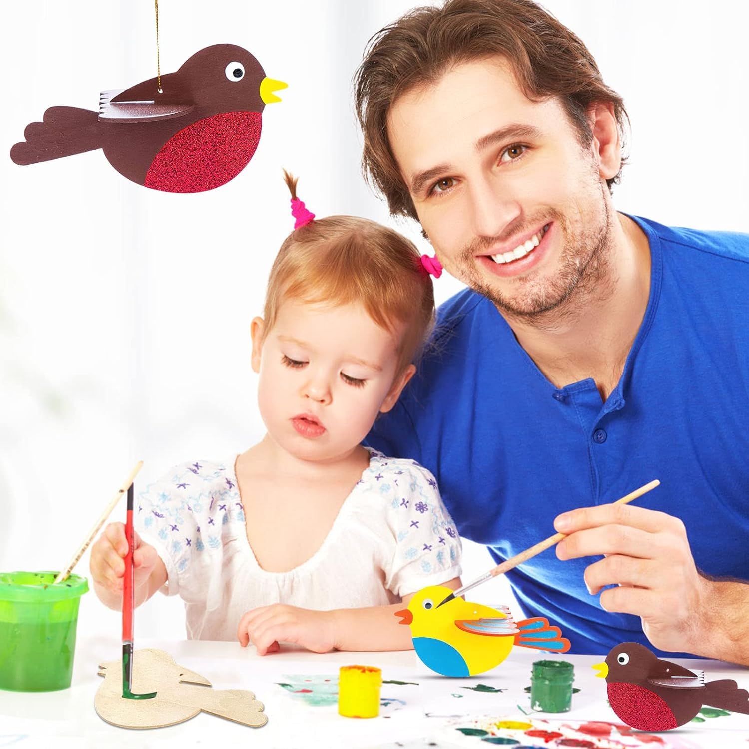 Man and child painting wooden birds with colorful paints on a white background