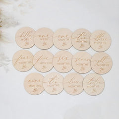 Round wooden discs with milestone text on a light background