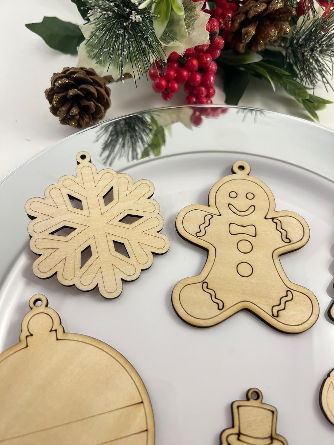 Wooden Christmas ornaments including a snowflake, gingerbread man, and ball on a white surface with decorative elements.