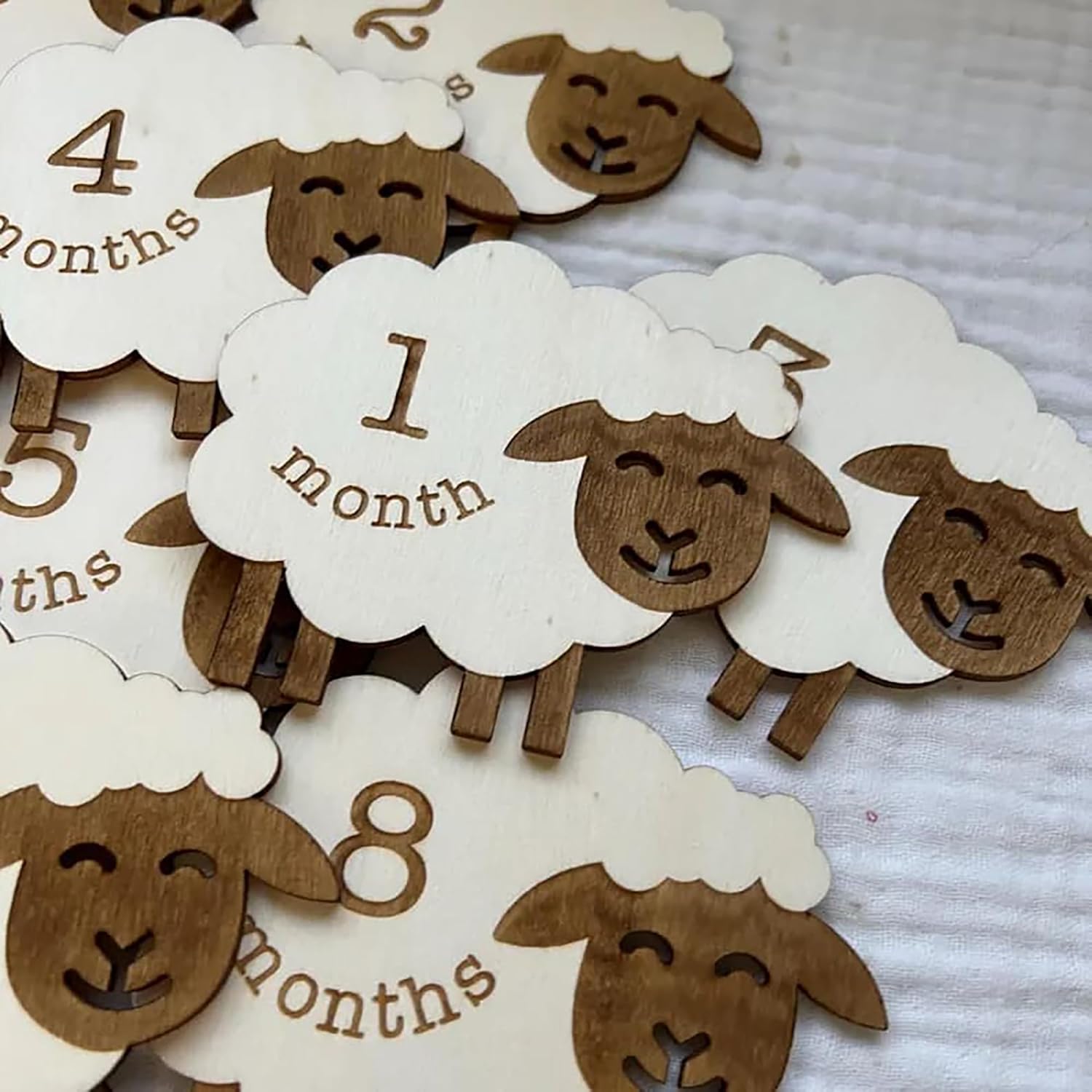 Wooden sheep-shaped age markers with months printed on them, arranged on a textured surface.
