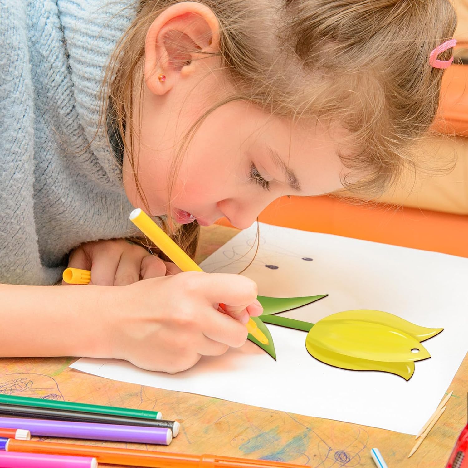 Child drawing with colored pencils on a table