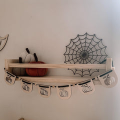 Wooden shelf with decorative items including pumpkins and a spider web design on the wall.