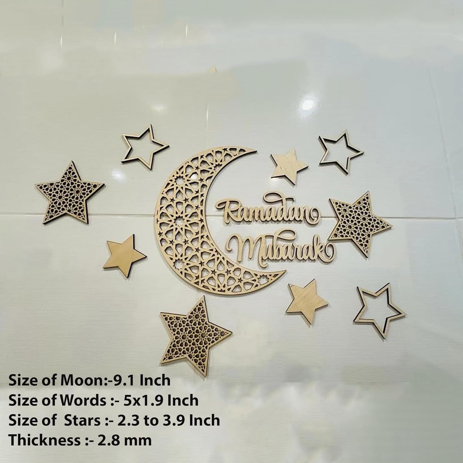 Decorative wooden cutout with 'Ramadan Mubarak' text, stars, and a moon on a white background.