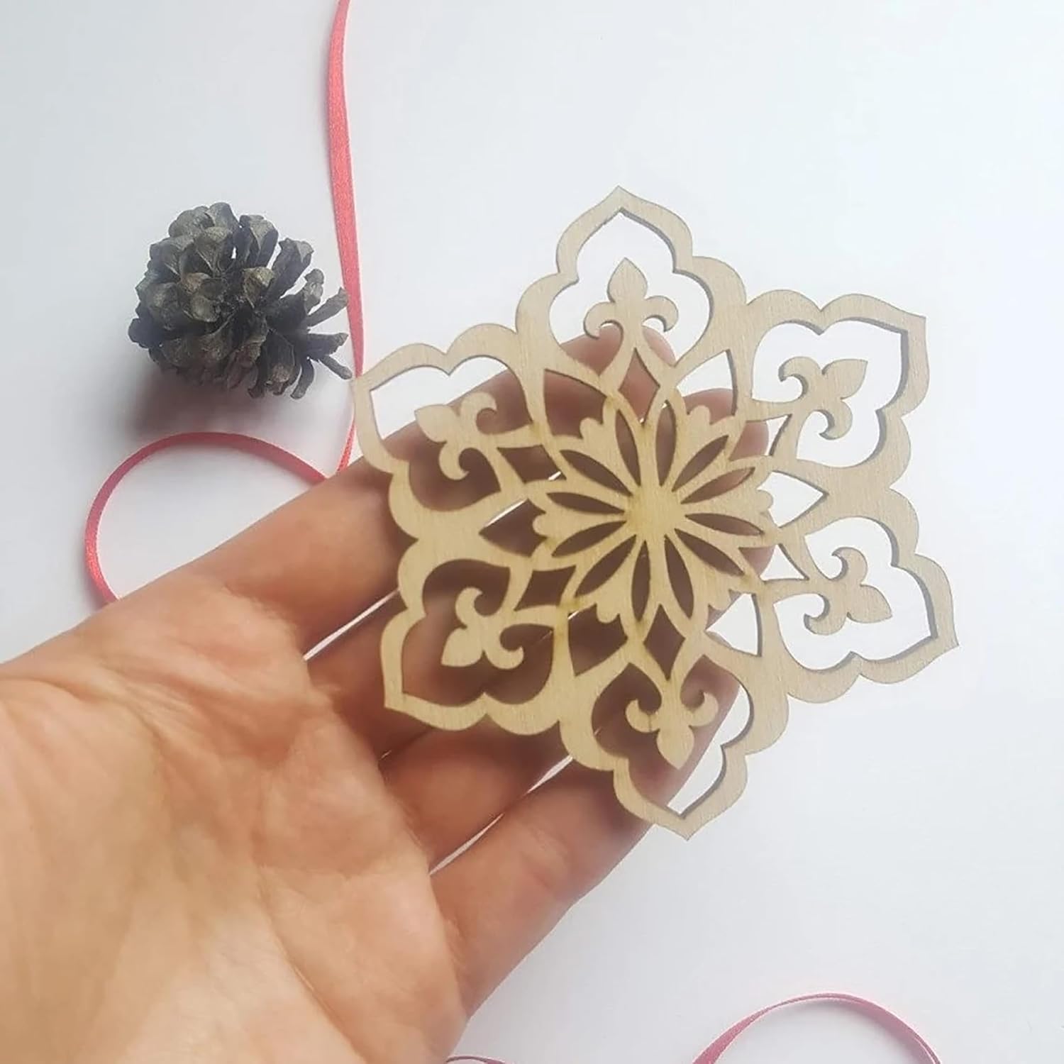Hand holding a decorative snowflake cutout with a white background
