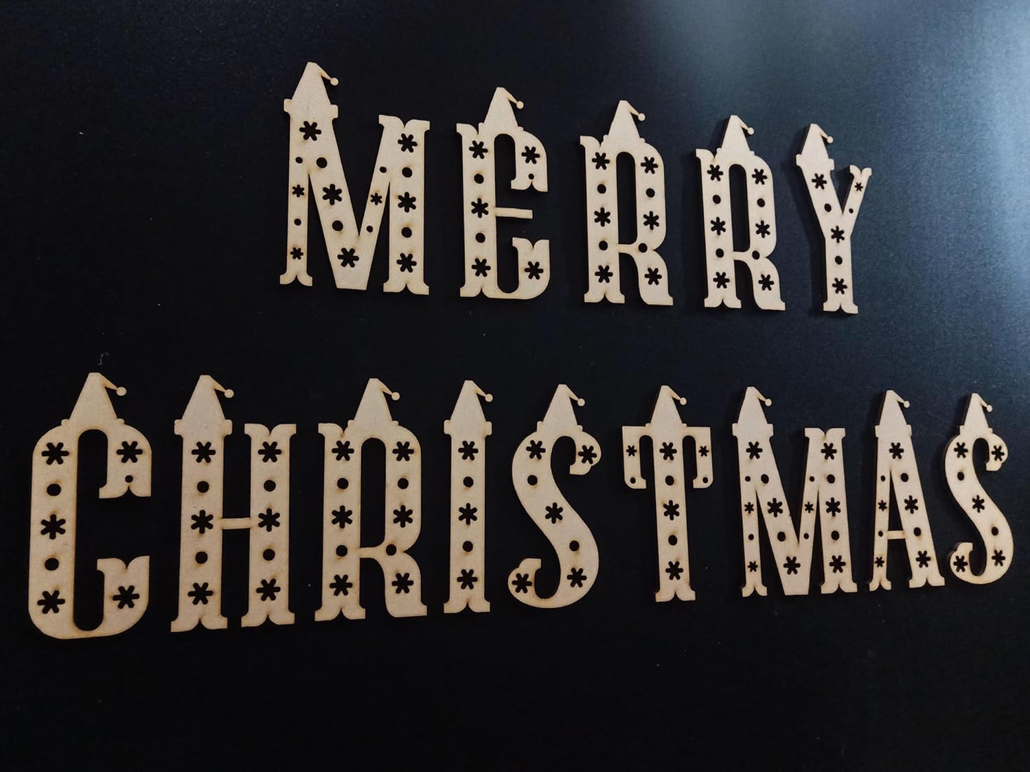 Wooden Christmas decoration with 'Merry Christmas' text on a black background