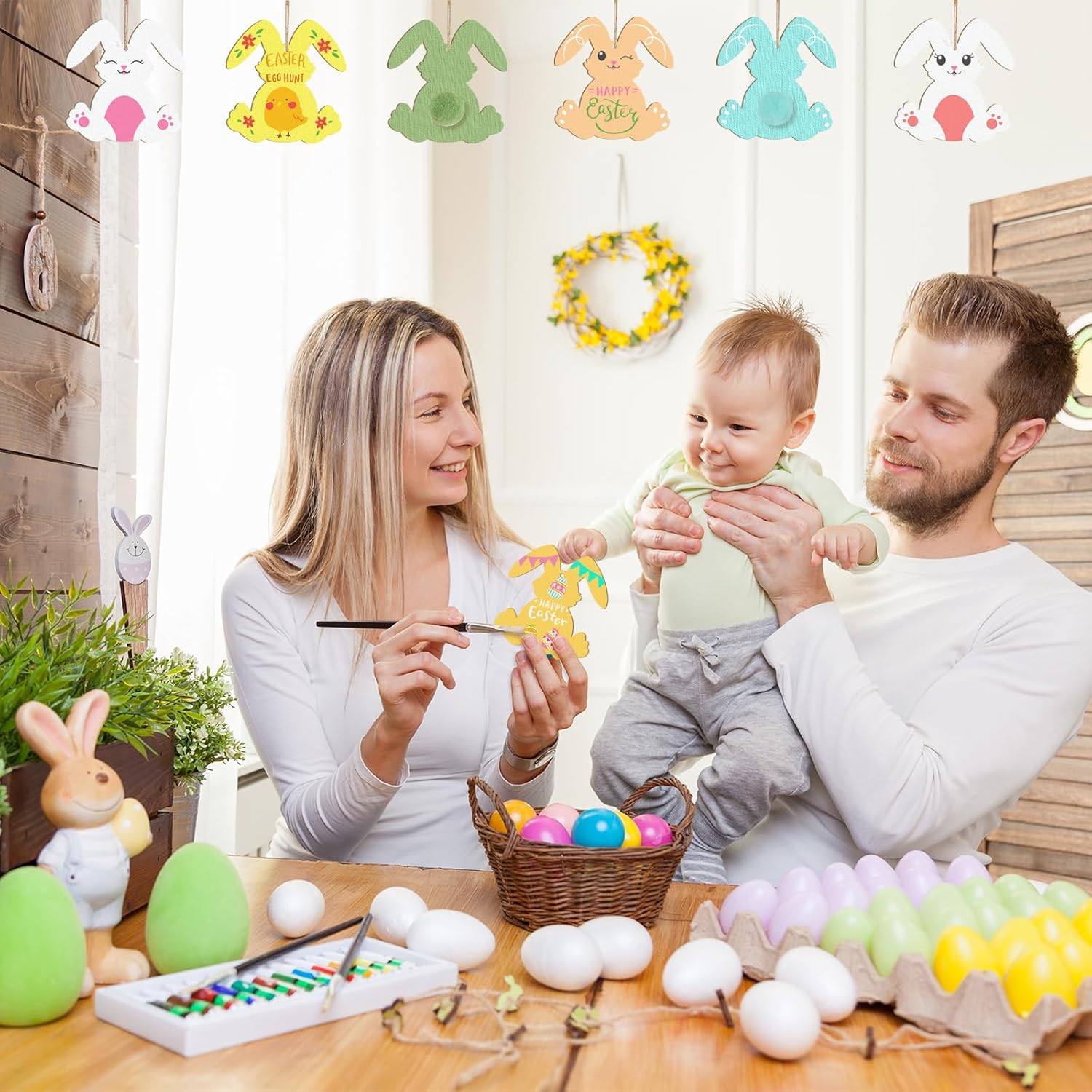 Family of three engaging in Easter activities with eggs and decorations.