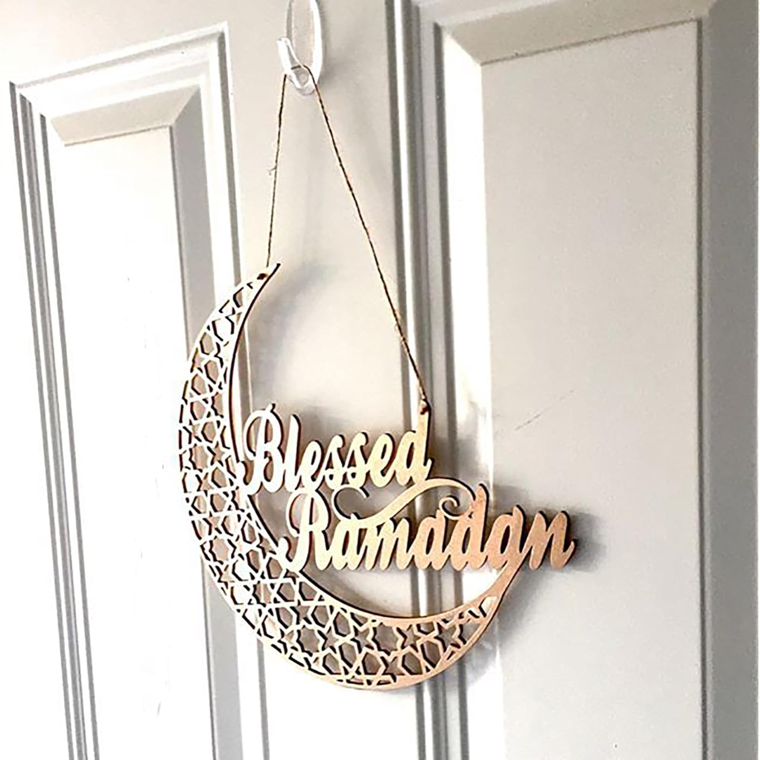 Decorative metal crescent moon with 'Blessed Ramadan' text hanging on a door.