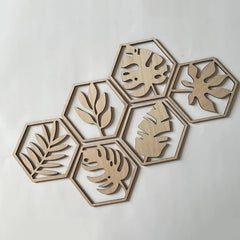 Hexagonal wooden wall art pieces with leaf patterns on a light gray background