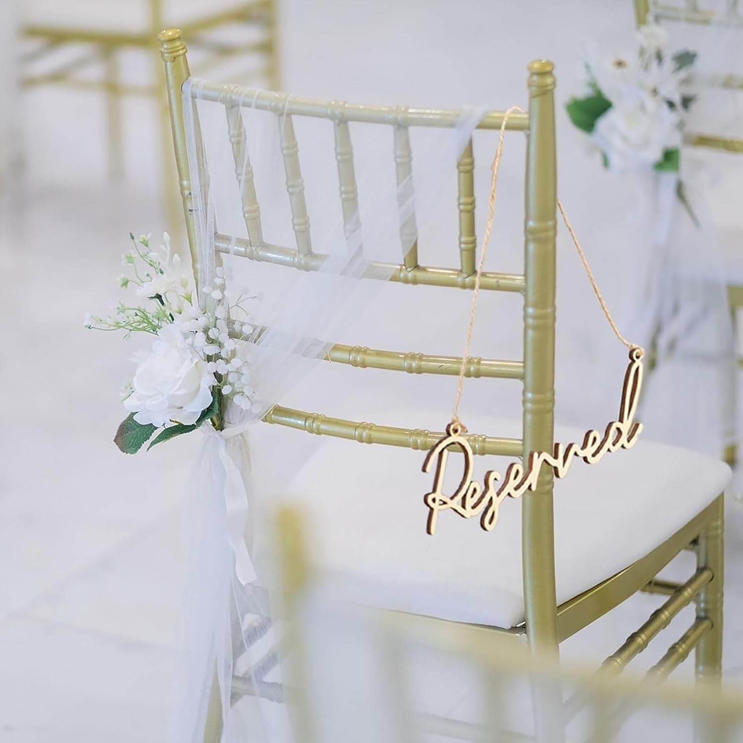 Gold 'Reserved' sign hanging on a chair with white flowers in an indoor setting