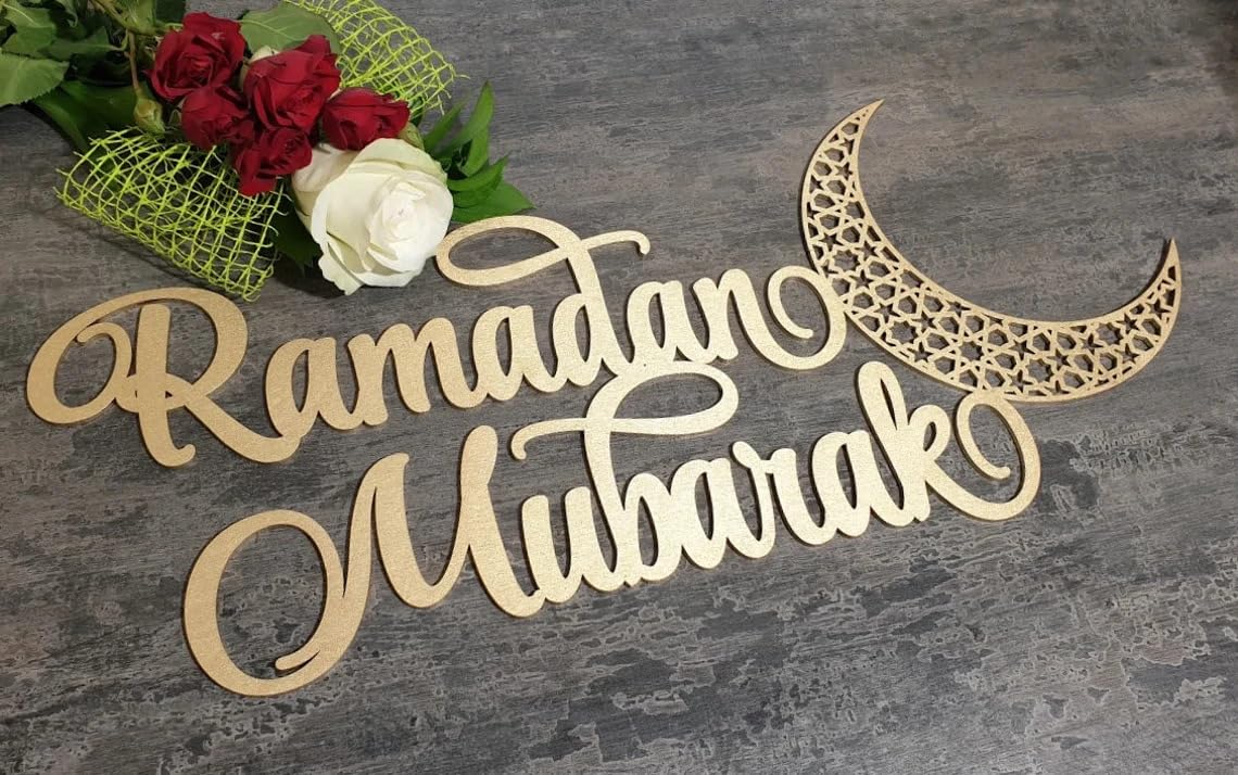 Wooden 'Ramadan Mubarak' sign with a moon symbol on a gray surface with flowers.