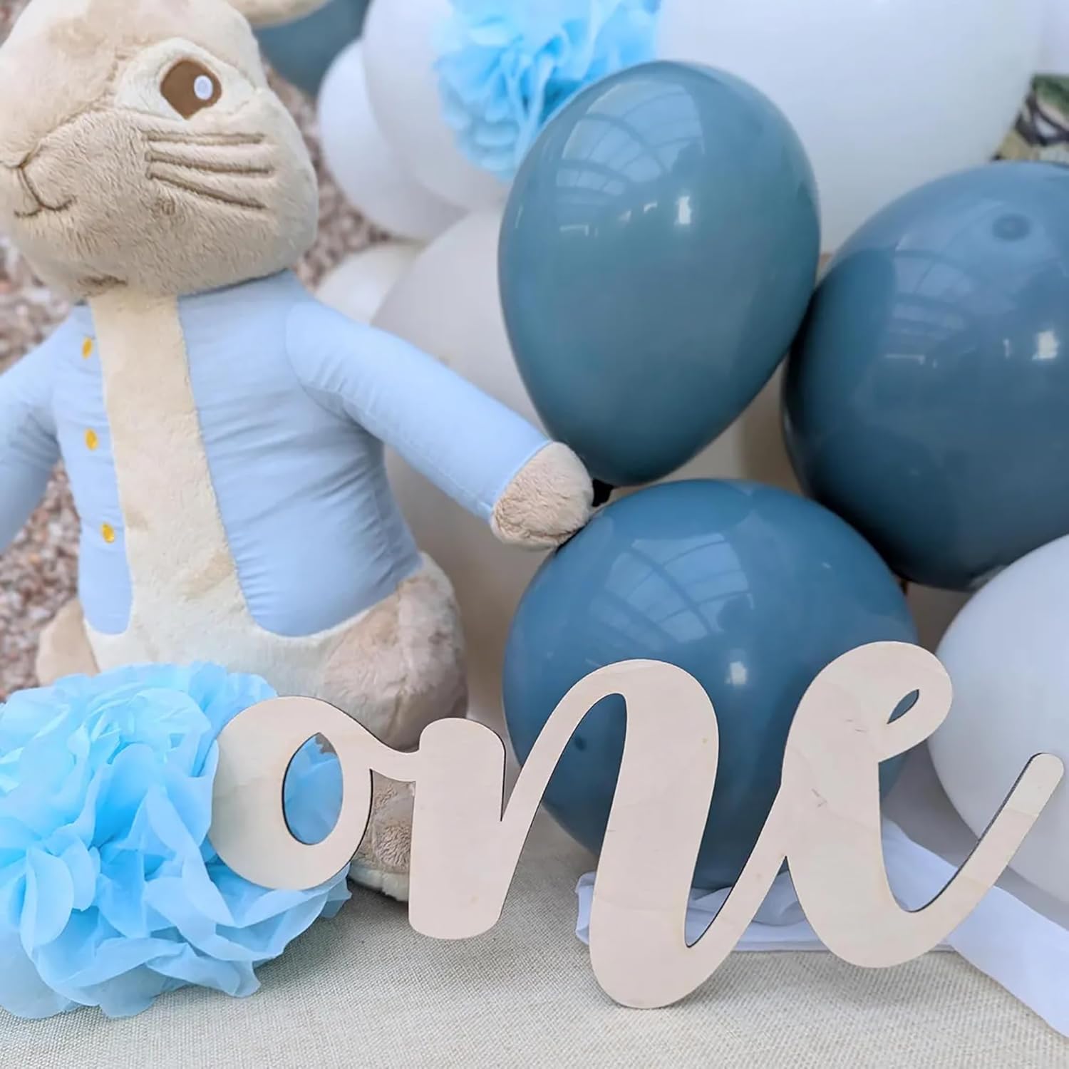 Baby shower decoration with plush toy, balloons, and 'one' sign.