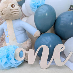 Baby shower decoration with plush toy, balloons, and 'one' sign.