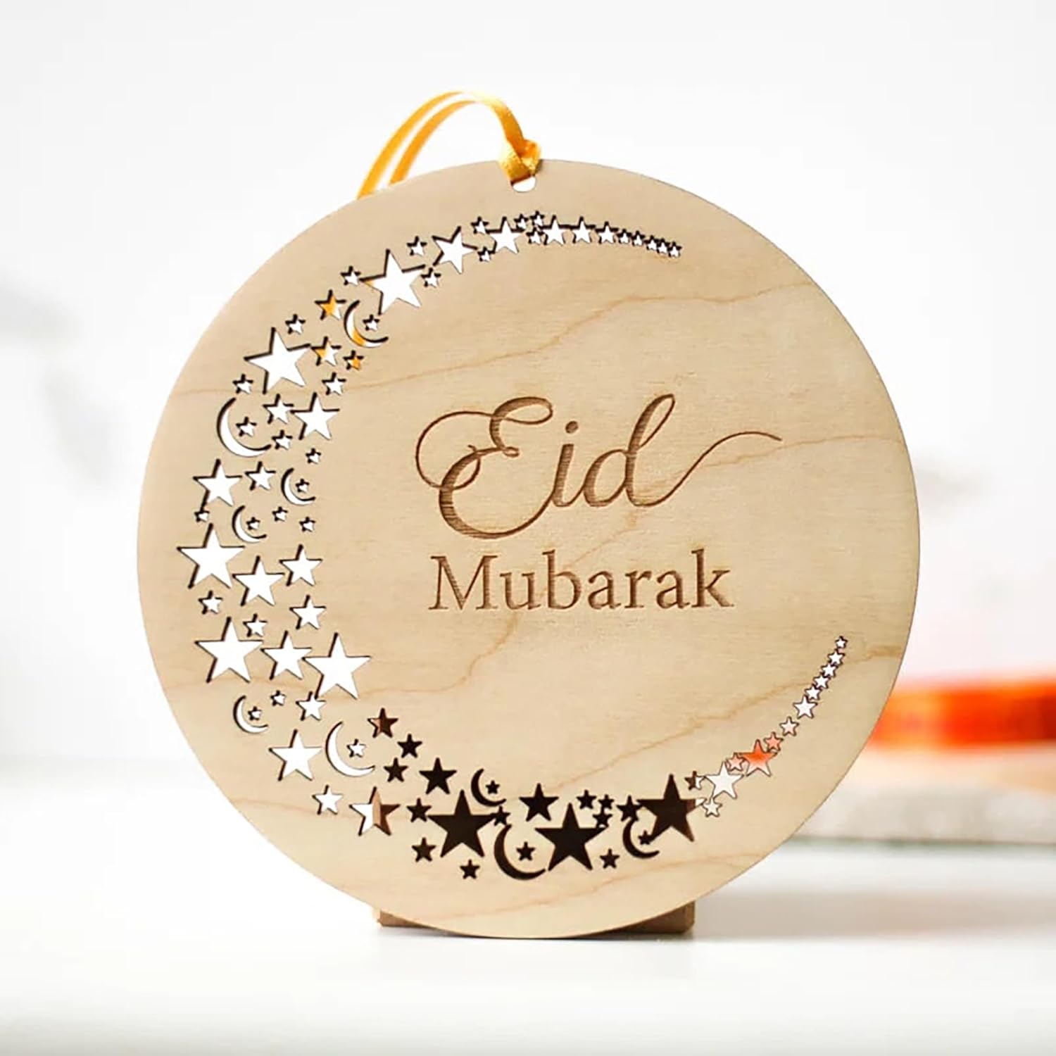 Wooden ornament with 'Eid Mubarak' text and star patterns on a white background