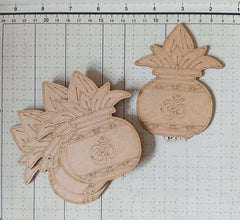 Two wooden pineapple-shaped decorations with Om symbols on a grid background