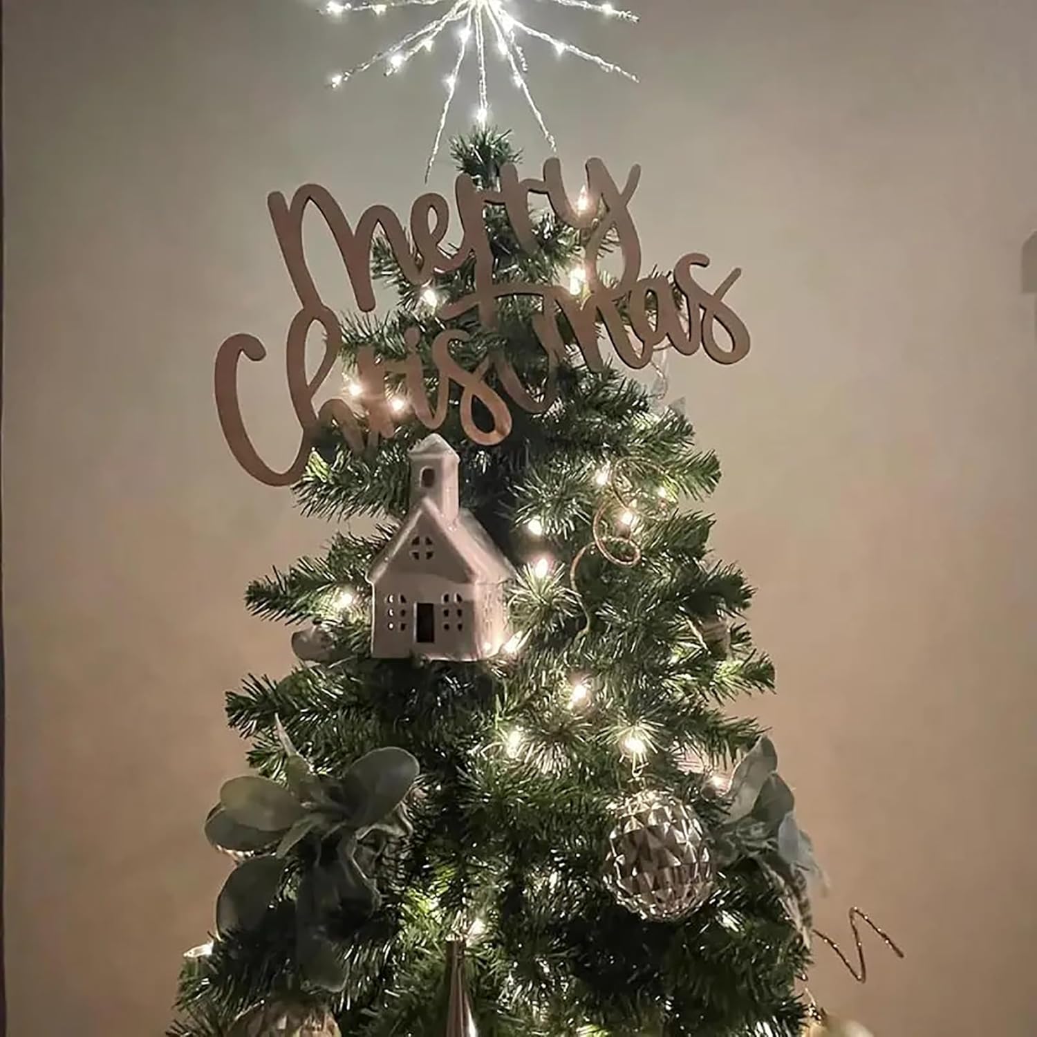 Decorated Christmas tree with 'Merry Christmas' sign and lights on a plain background