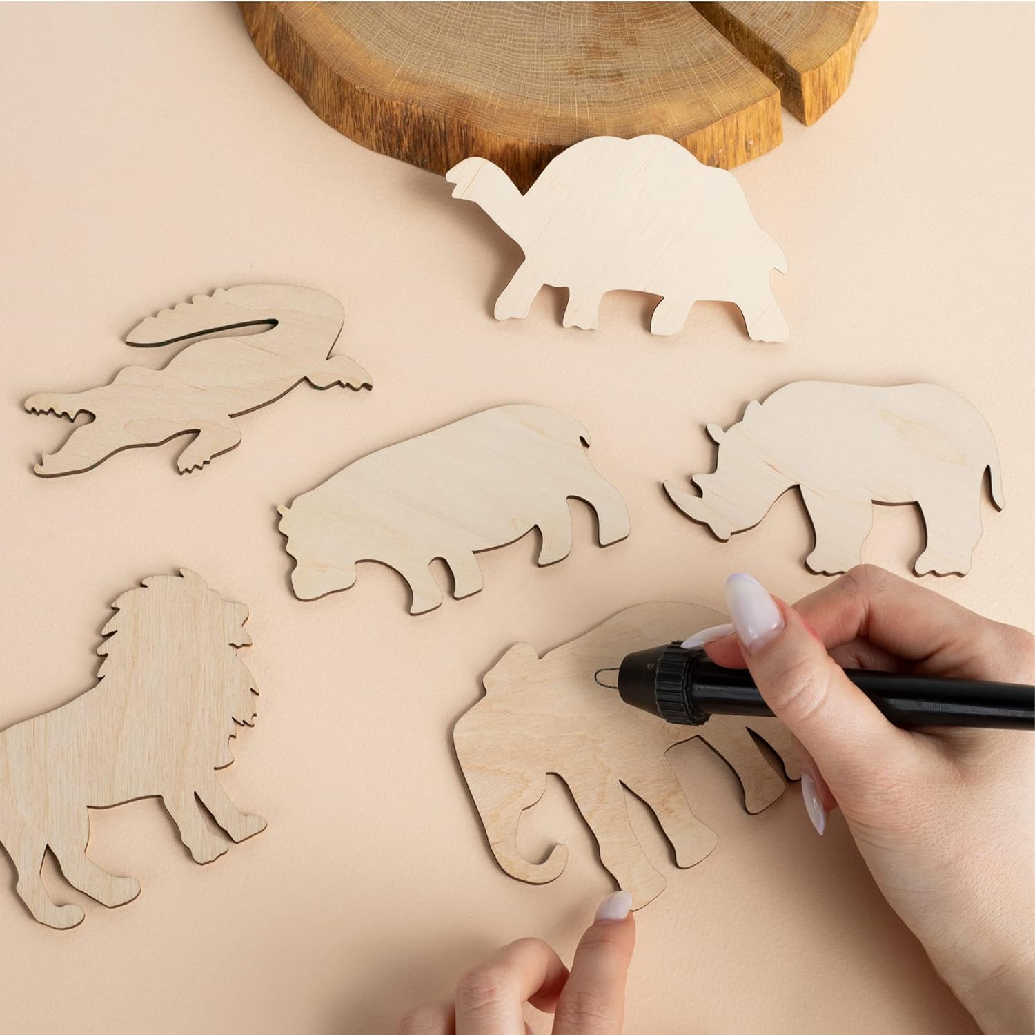 Wooden animal cutouts on a wooden surface with hands using a marker.