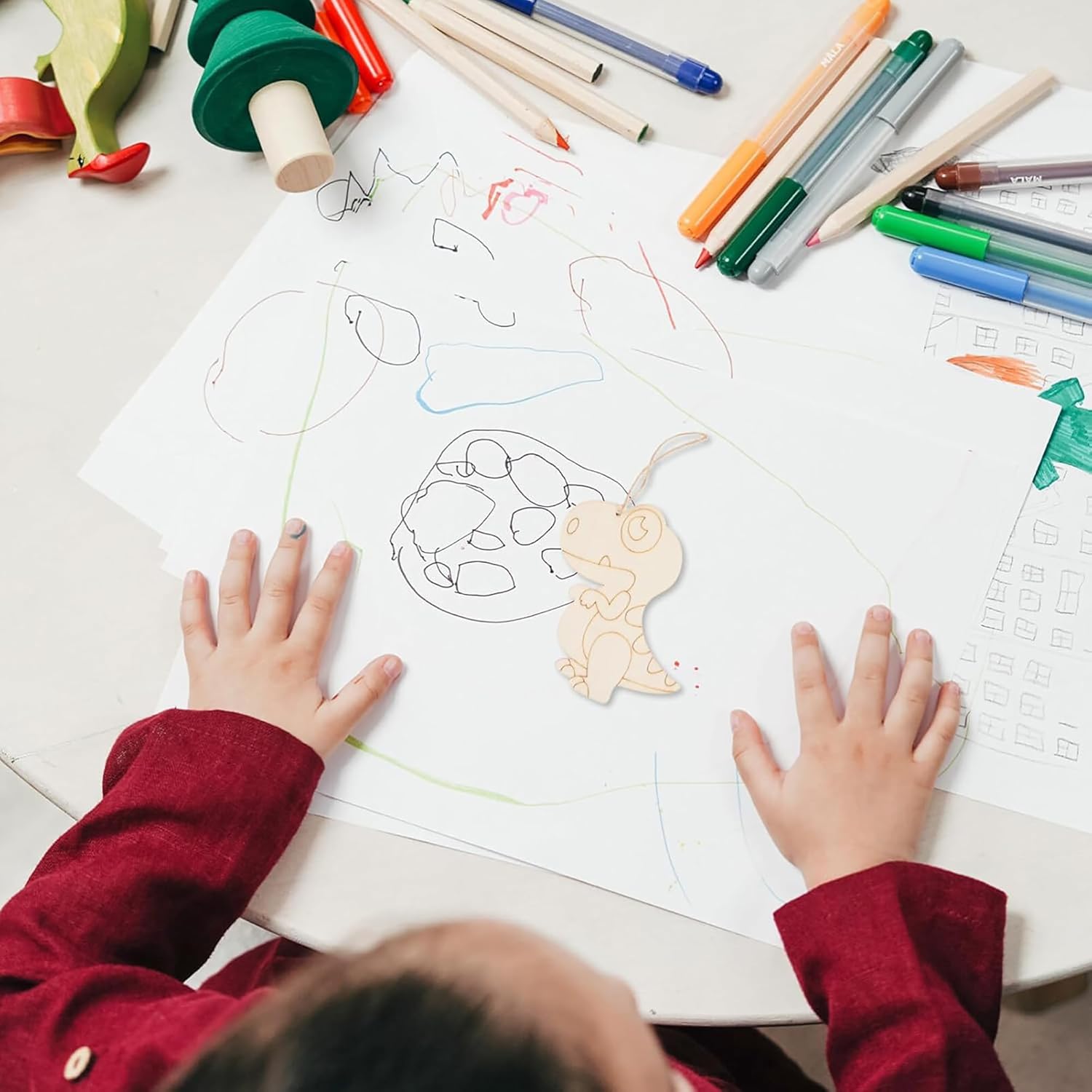 Child's hands on a drawing with colored pencils and markers on a table
