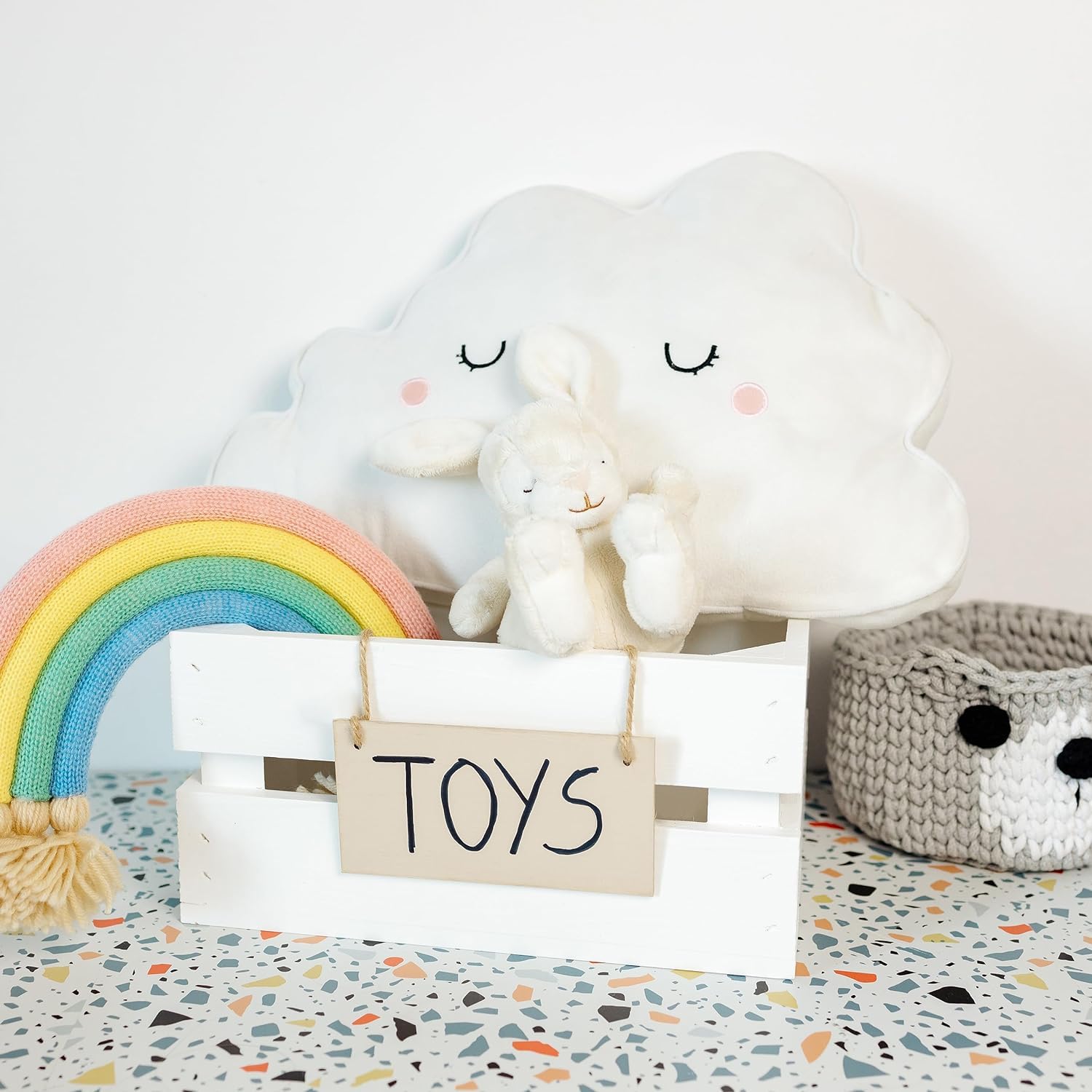Toy box with cloud-shaped lamp, rainbow, and teddy bear on a terrazzo-patterned floor.
