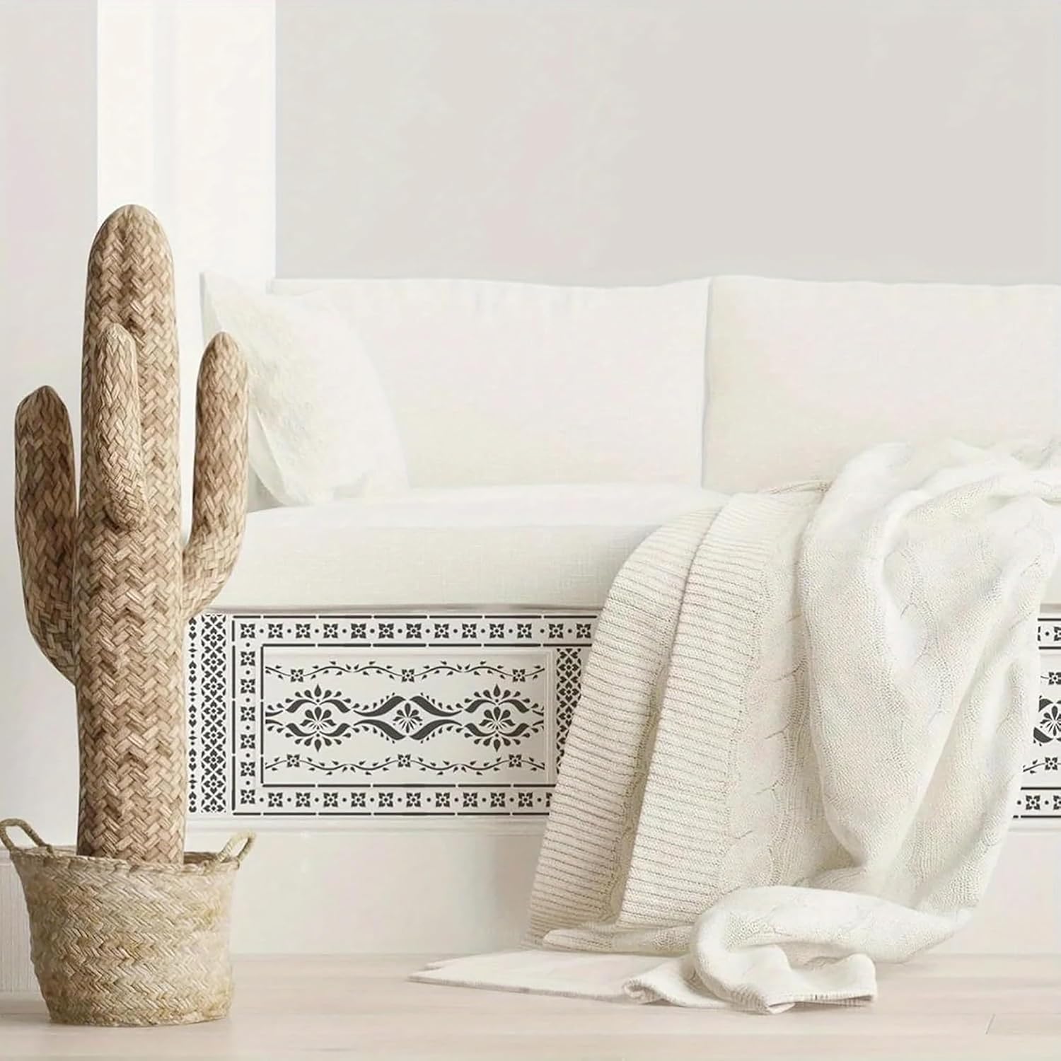 Decorative cactus and white blanket on a white sofa with a white wall background