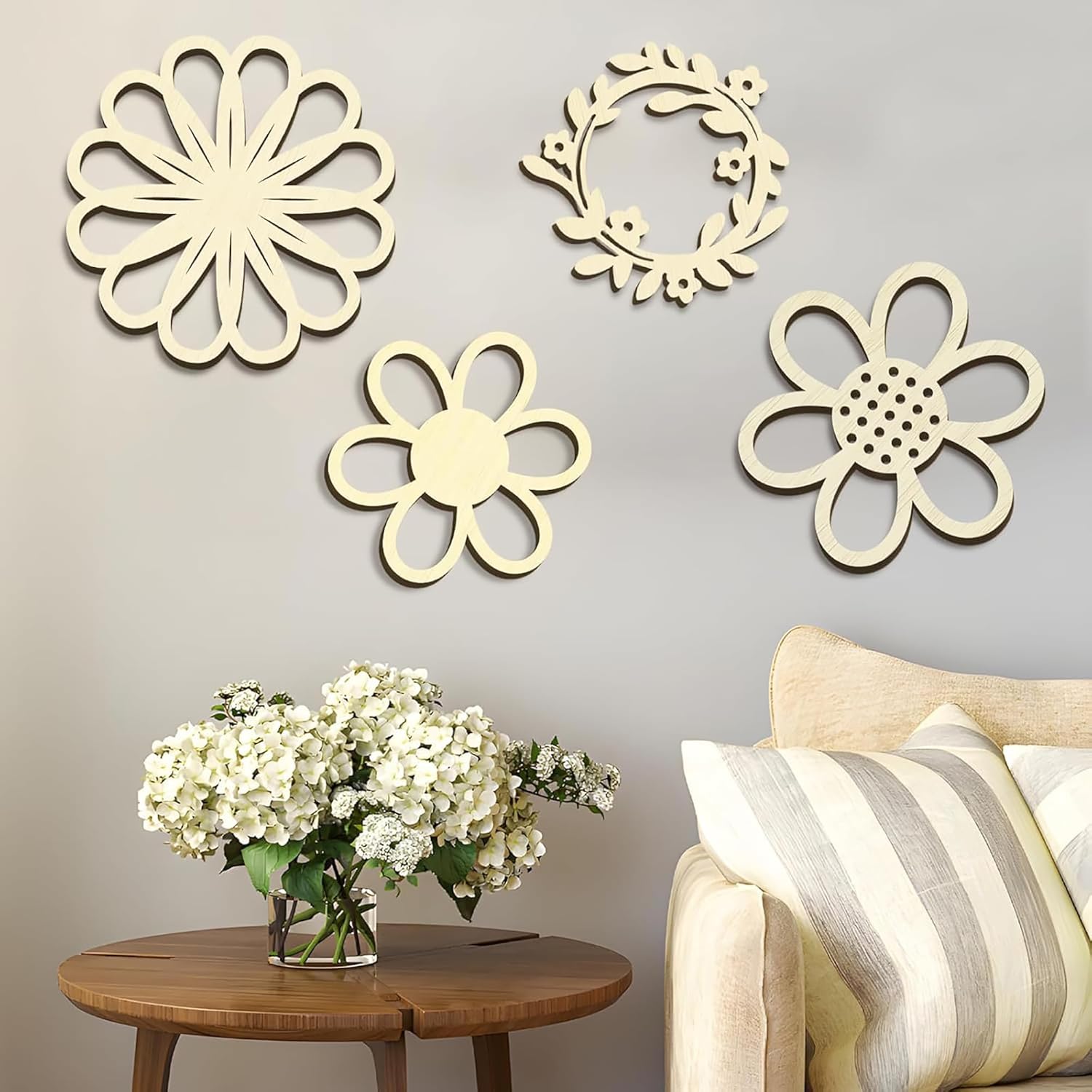 Decorative wall art with floral designs on a gray wall above a wooden table with flowers and a sofa.