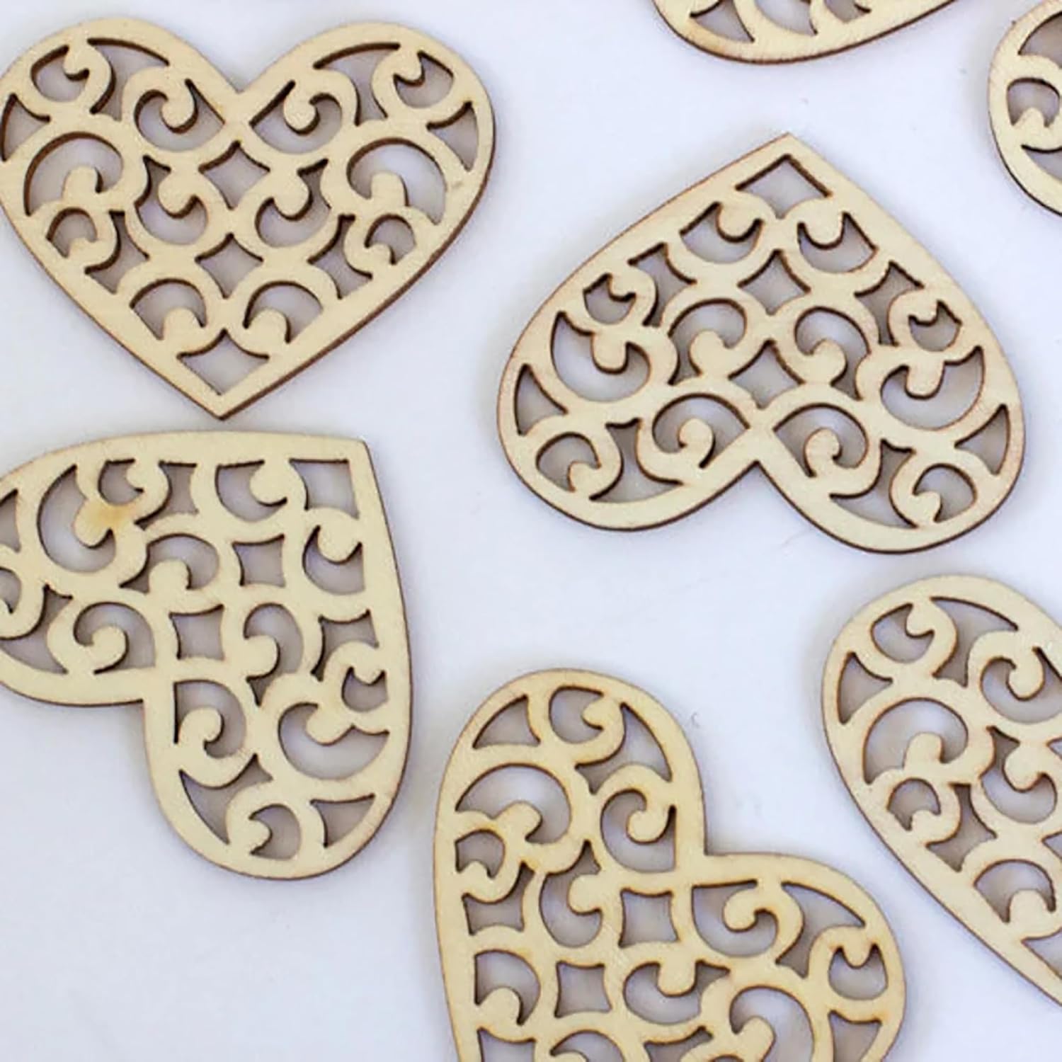 Wooden heart-shaped decorations with intricate cut-out patterns on a white background