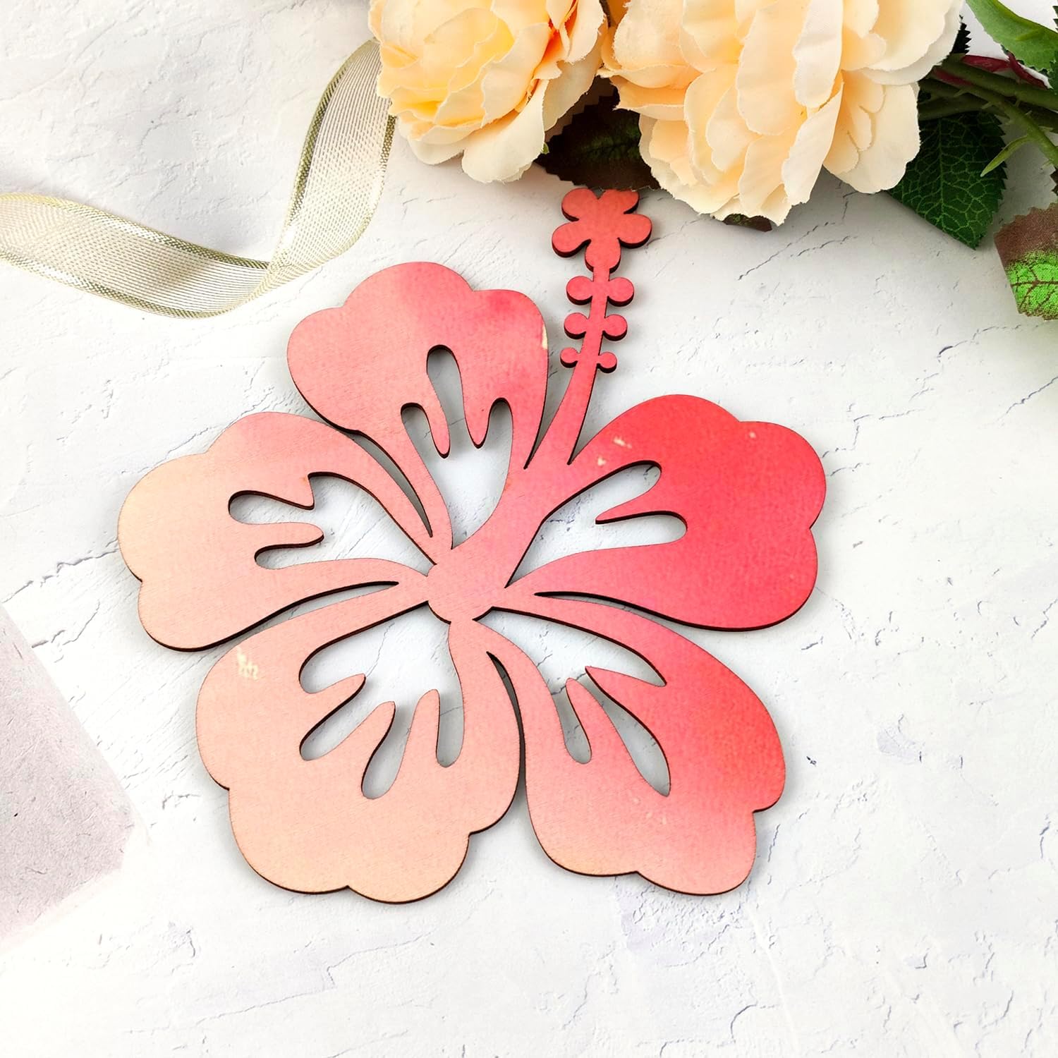 Decorative pink flower-shaped object on a textured white surface with flowers in the background