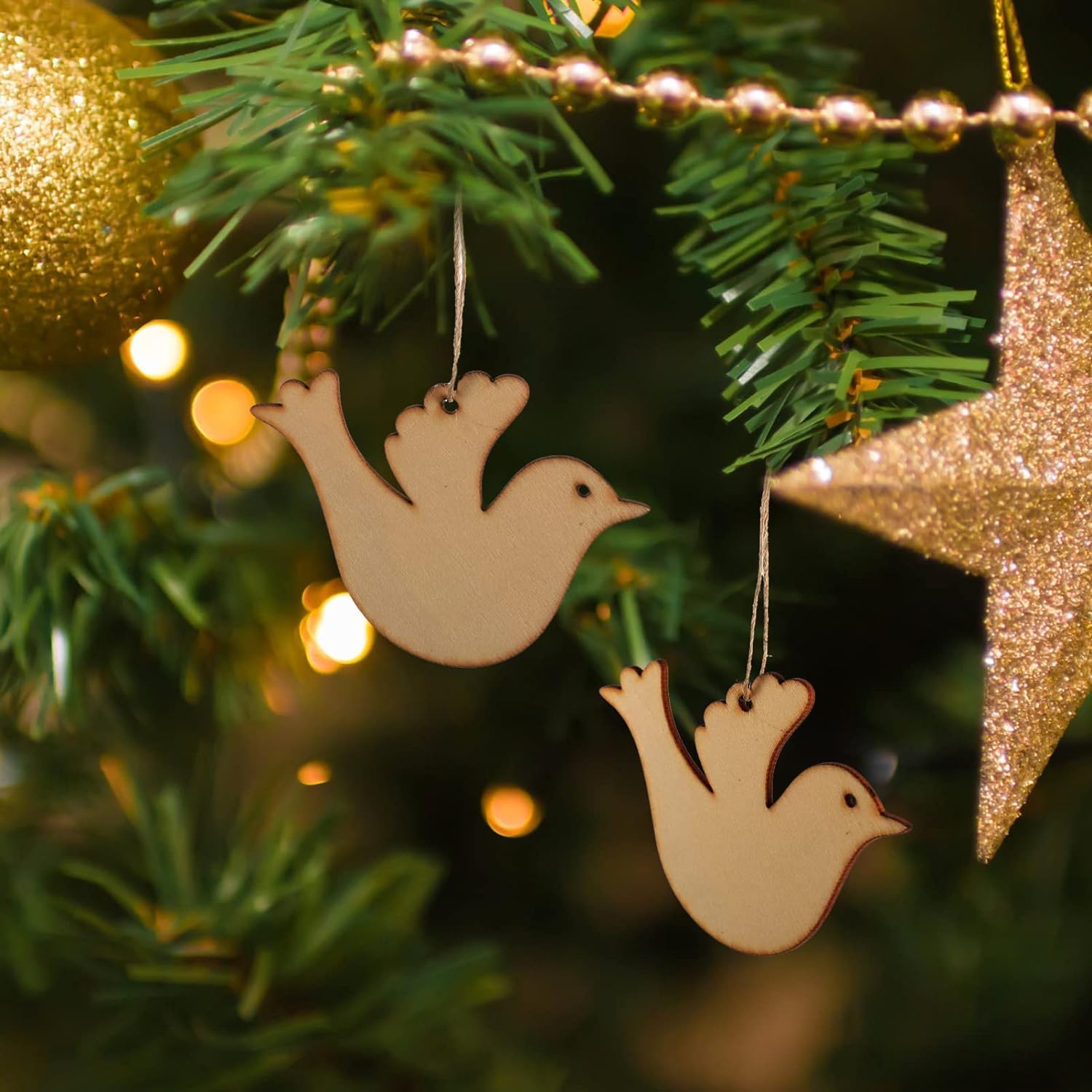 Wooden dove ornaments hanging on a Christmas tree with blurred lights in the background