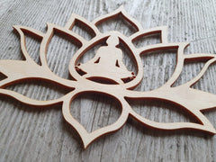 Wooden lotus flower with a meditating figure inside on a wooden surface