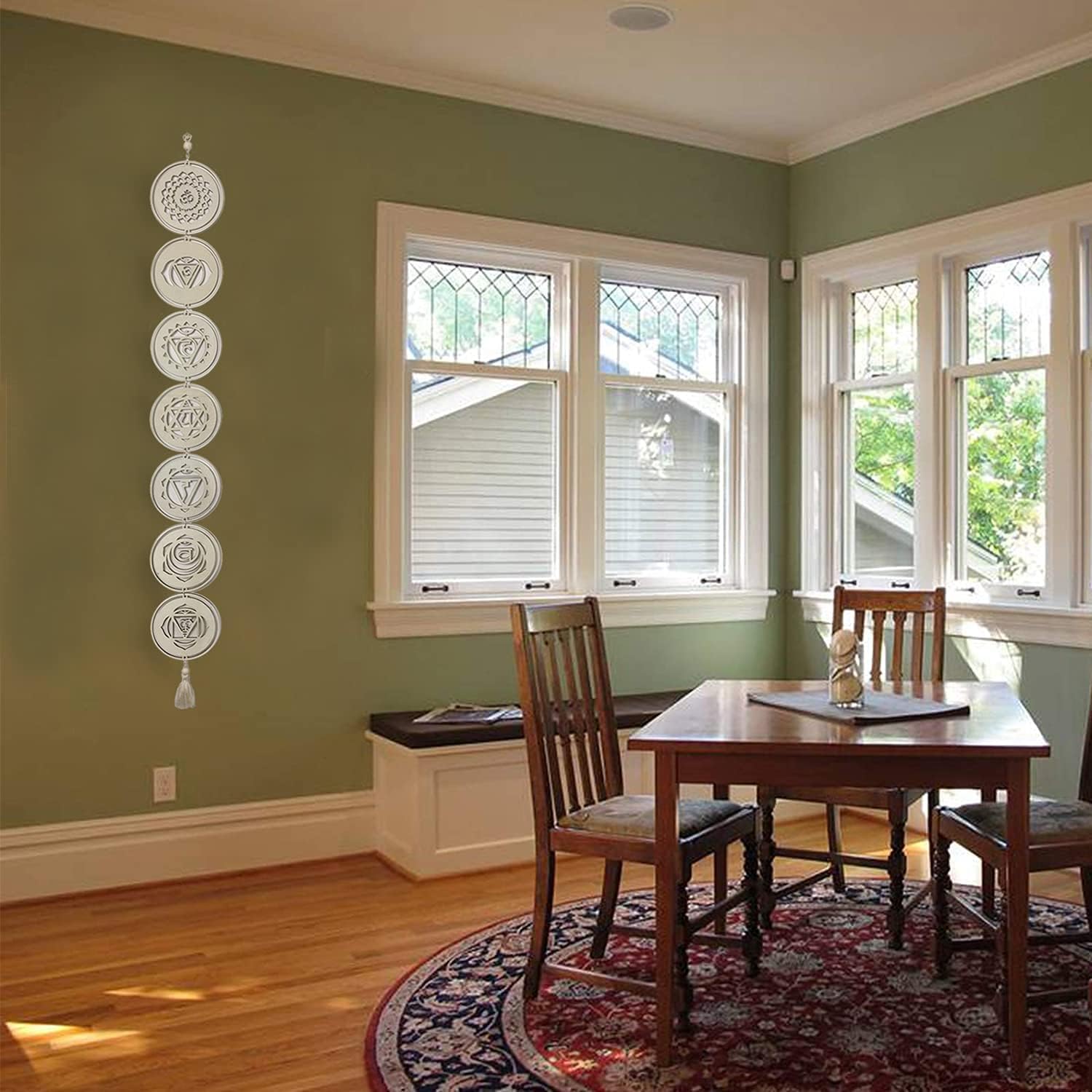 Dining room with wooden table and chairs, green walls, and large windows.